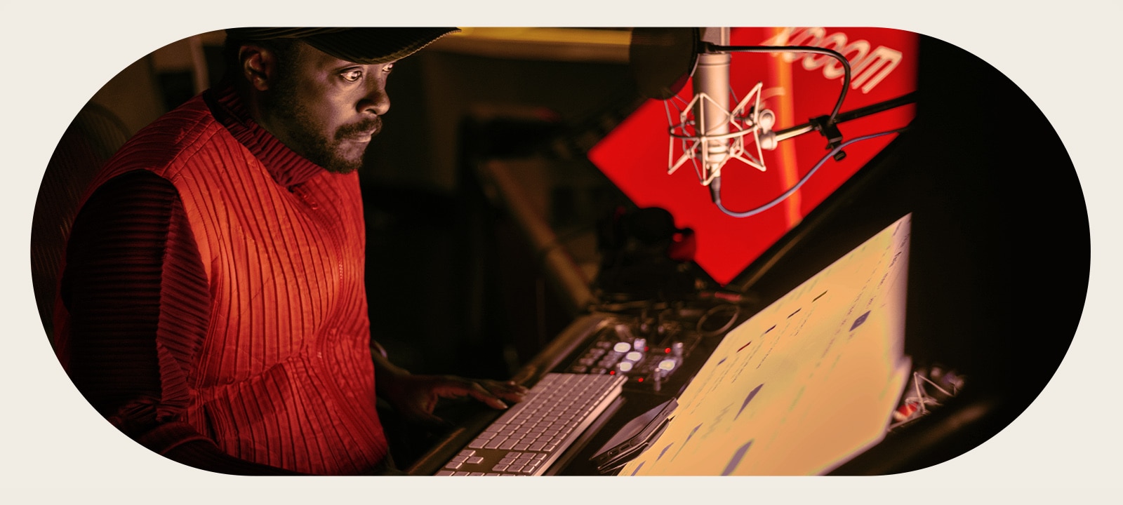 will.i.am is working in studio looking at a screen placed below a mic.